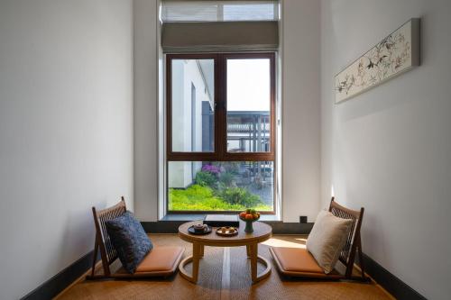 a room with two chairs and a table and a window at POKKEI Hotel Shaoxing in Shaoxing