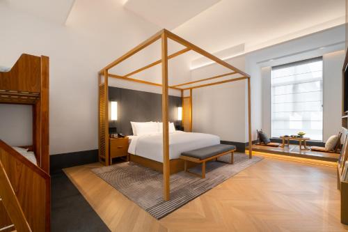 a bedroom with a large canopy bed with a bench at POKKEI Hotel Shaoxing in Shaoxing