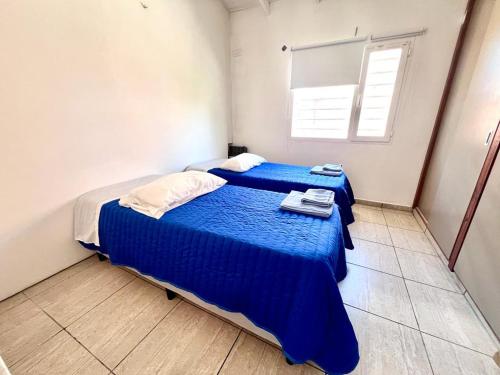 1 dormitorio con 2 camas con sábanas azules y ventana en Calle Republica de Italia en Neuquén