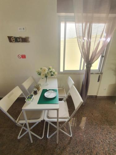 a white table with white chairs and a window at Hospedagem Emanuel in Caneças