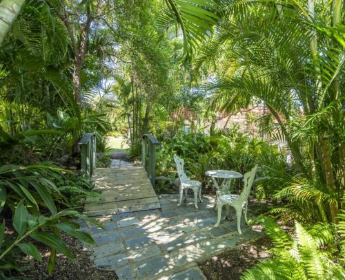 two chairs and a table on a wooden walkway with trees at COST EFFECTIVE ISLAND ESCAPE! Studio Unit, Nelly Bay in Nelly Bay