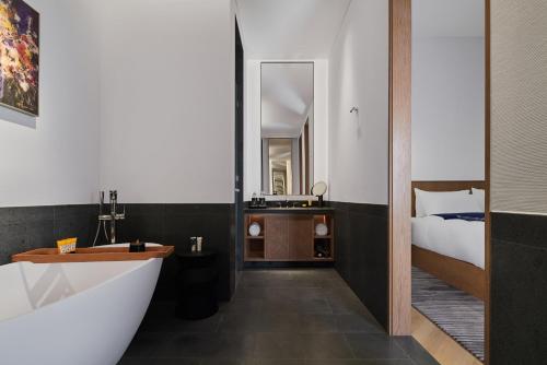 a bathroom with a bath tub and a bed at POKKEI Hotel Shaoxing in Shaoxing