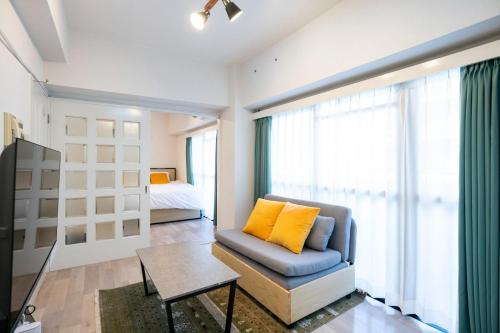 a living room with a couch and a yellow pillow at REBANGA Juso Apartment in Osaka