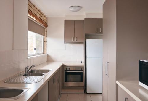 a kitchen with a white refrigerator and a sink at Coastal Comfort Motel in Narooma