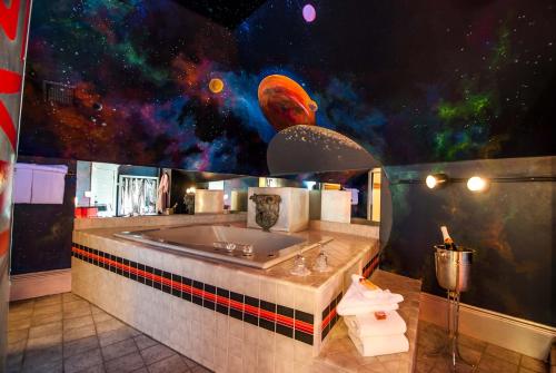 a bathroom with a large bath tub with a space themed wall at The Anniversary Inn - Logan in Logan