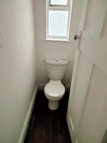 a small bathroom with a toilet and a window at Comfort zone accommodation near care home in Coseley