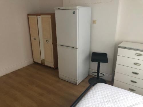 Comfort zone accommodation near care home في Coseley: غرفة نوم مع ثلاجة بيضاء وكرسي