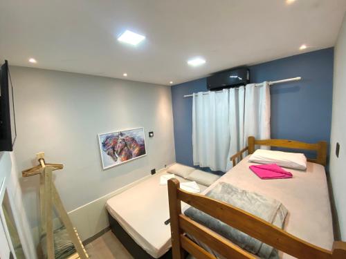 Habitación pequeña con cama y cruz en la pared en valenshostel en Angra dos Reis