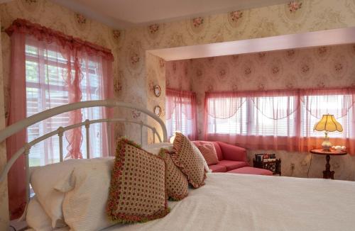a bedroom with a bed and a chair and windows at The Anniversary Inn - Logan in Logan