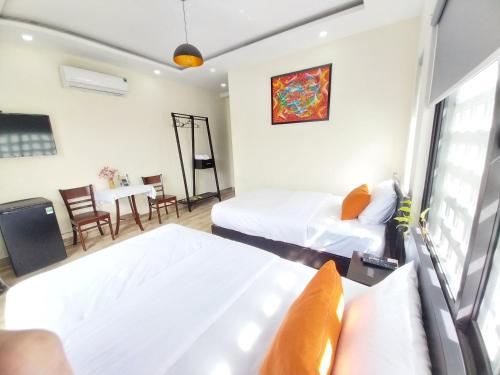 ein Hotelzimmer mit 2 Betten und einem Tisch in der Unterkunft Giao Hòa Homestay Hội An in Hoi An