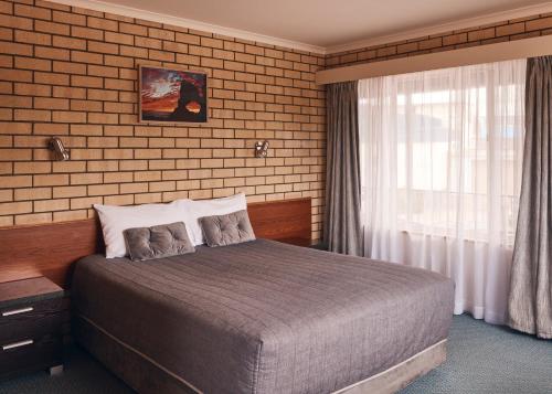 a bedroom with a large bed and a window at Coastal Comfort Motel in Narooma