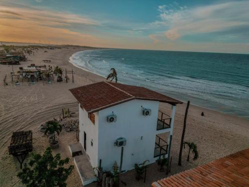 a man standing on the roof of a house on the beach at Chalé Galo Preto in Galinhos