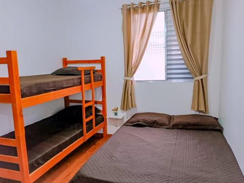 a bedroom with two bunk beds and a window at Apartamento Vista Linda - com suíte - Bertioga - Prox ao SESC, Riviera, Indaiá in Bertioga