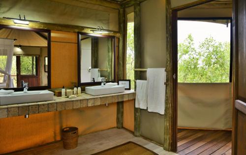 baño con 2 lavabos y espejo grande en Ghoha Hills Savuti Lodge, en Savuti