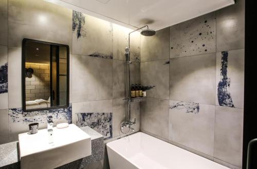 a bathroom with a sink and a tub and a mirror at Mari Hotel Terminal Branch in Jeonju