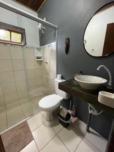La salle de bains est pourvue de toilettes, d'un lavabo et d'un miroir. dans l'établissement Casa inteira sozinha no pátio com estacionamento - Guarda do Embaú, à Guarda do Embaú