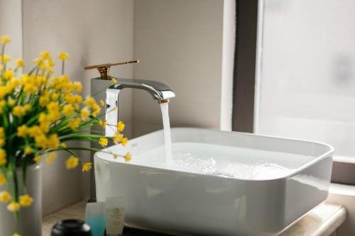a sink with a water faucet and flowers on a counter at TrangTrang Premium Hotel & Sky Bar in Hanoi