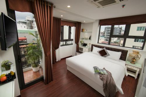1 Schlafzimmer mit einem weißen Bett und einem Balkon in der Unterkunft TrangTrang Premium Hotel & Sky Bar in Hanoi