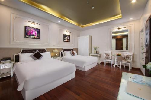a bedroom with two white beds and a table at TrangTrang Premium Hotel & Sky Bar in Hanoi