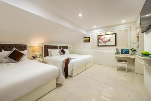 a hotel room with two beds and a desk at TrangTrang Premium Hotel & Sky Bar in Hanoi