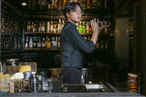 a man standing behind a bar with his hand up at TrangTrang Premium Hotel & Sky Bar in Hanoi