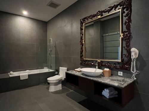 a bathroom with a sink and a toilet and a mirror at Tabebuya Resto & Resort in Kesembu