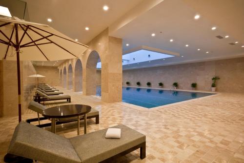 a swimming pool with a table and chairs and an umbrella at Howard Johnson Tongfang Plaza Zhuji in Zhuji