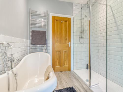 a white bathroom with a tub and a shower at Creamore Grove in Wem