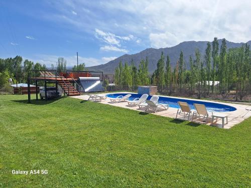 a swimming pool with lounge chairs in a yard at Cabañas Alpinas in Mendoza