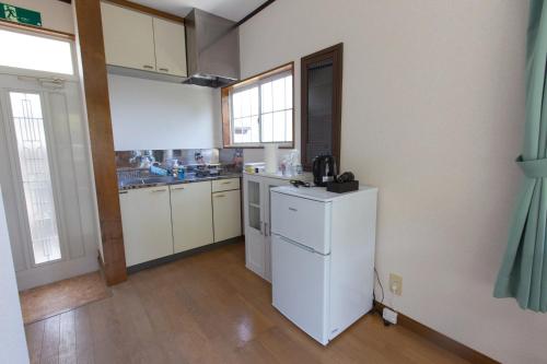a kitchen with white cabinets and a white refrigerator at 森の風 in Higashiizu