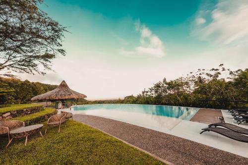 Pilar的住宿－Ilaya Highland Resort，一个带椅子和遮阳伞的度假村游泳池