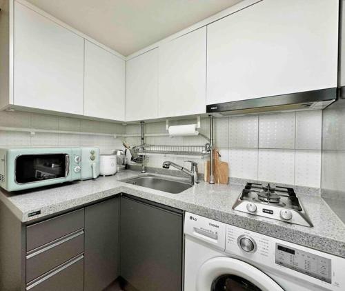 a kitchen with a sink and a washing machine at Gasan Duplex - Female Only in Seoul