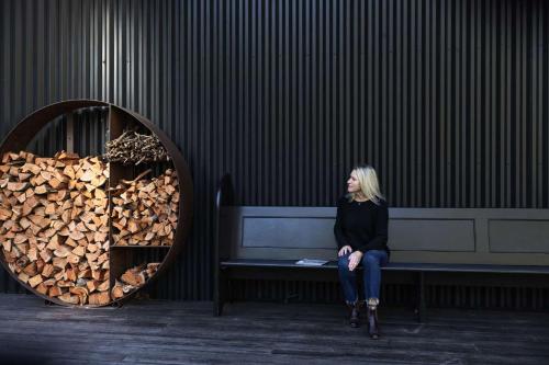 a woman sitting on a bench next to a pile of wood at Black Star, Kangaroo Valley in Kangaroo Valley