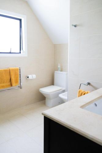 a white bathroom with a toilet and a sink at FOREST WATERS in Haruru