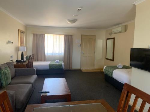 Habitación de hotel con 2 camas y sofá en Armidale Pines Motel, en Armidale