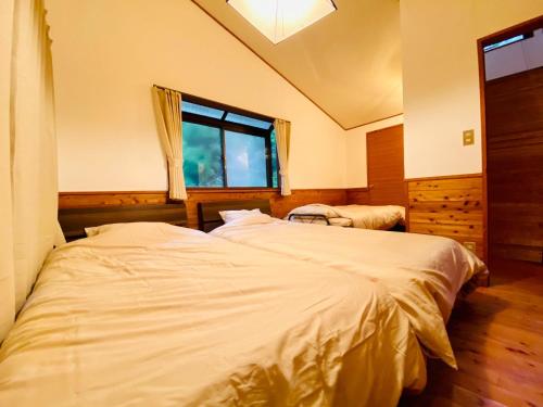 two twin beds in a room with a window at Aso - Cottage - Vacation STAY 83363 in Aso