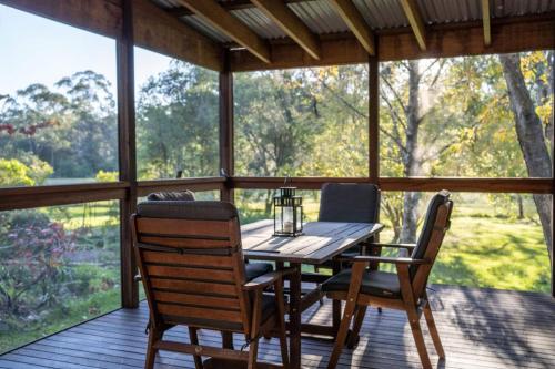 a screened in porch with a wooden table and chairs at KV Cottage, Kangaroo Valley in Kangaroo Valley