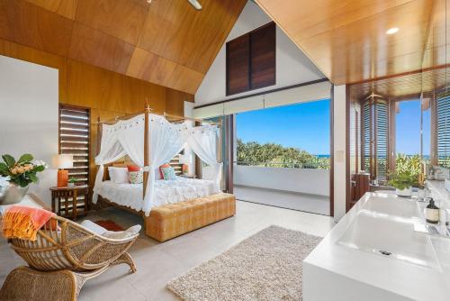 a master bedroom with a bed and a tub at Kingscliff Balinese Beachfront Retreat in Kingscliff
