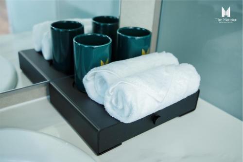 a shelf with towels and cups in a bathroom at The Mansion Hotel Bien Hoa in Bien Hoa