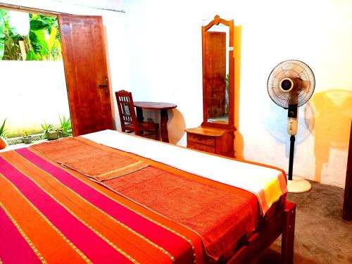 a bedroom with a bed and a fan and a table at Mount Rest Villa in Hikkaduwa