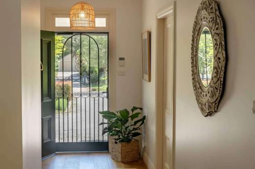 a hallway with a door with a plant and a mirror at Somerset, Berrima, Southern Highlands in Berrima