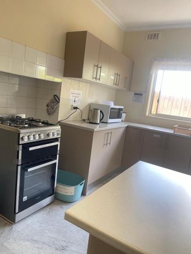 a small kitchen with a stove and a microwave at Werribee DGH Accommodation in Werribee
