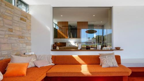 un sofá naranja en una sala de estar con una gran ventana en Solina - Ettalong Beach en Ettalong Beach