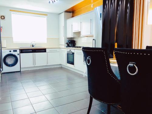 a kitchen with white cabinets and black chairs at Manchester City home with parking in Manchester