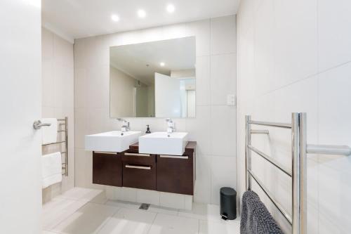 un baño con dos lavabos y un espejo en Chilling at the Cayman, en Mount Maunganui