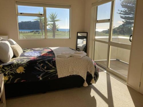 Un dormitorio con una cama y una ventana grande. en Marine Magic, en Mount Maunganui