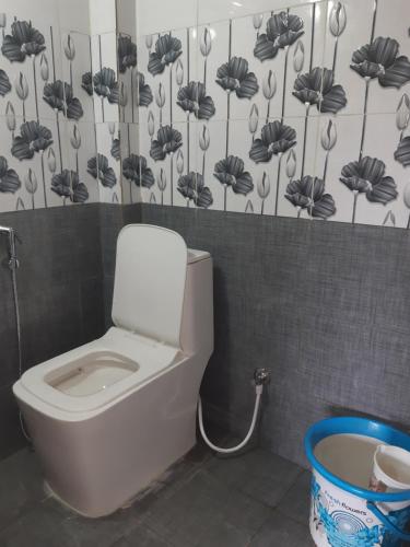 baño con aseo con un estampado de flores en la pared en Riverview homestay, en Vālpārai