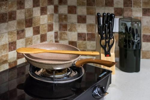 a pan on top of a stove with wooden utensils at Pondok Arya Kuta Villas by Kamara in Kuta