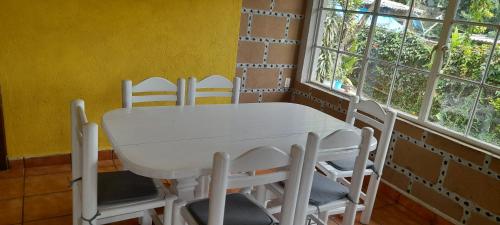 un tavolo bianco con sedie in una stanza con finestre di Casa Sauces a Tepoztlán