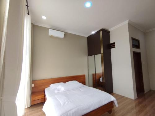 a bedroom with a white bed and a black cabinet at Saira Hotel dan Homestay Syariah in Sleman